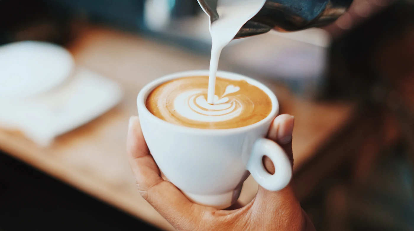 Barista nalieva mliečnu penu do šálky cappuccina